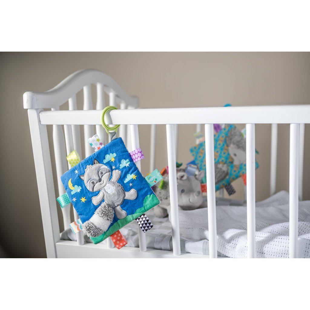 Scene of the raccoon teething toy hanging from a crib.