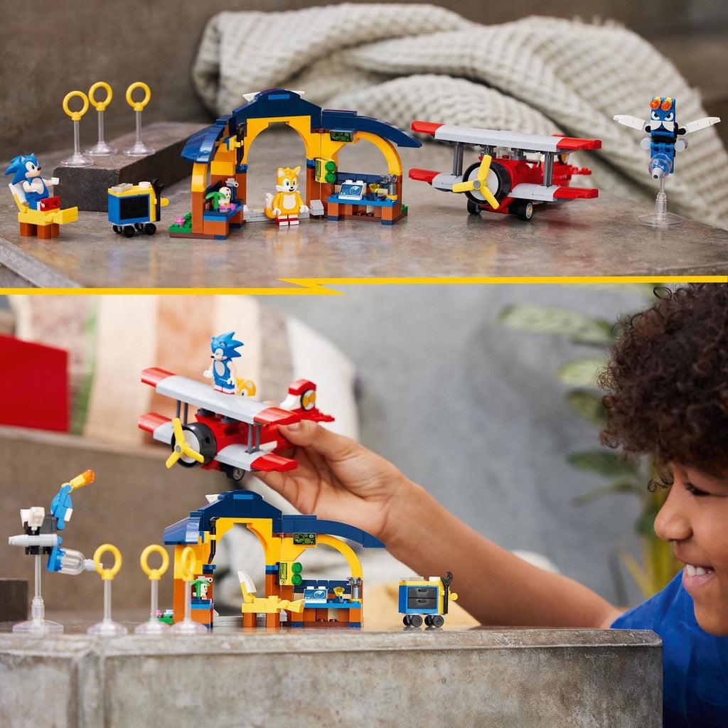 this image shows a kid playing with the LEGO sonic set. firsy tails in in the workshop while sinic relaxes in a chair before they take off in the airplane with tails as the pilot