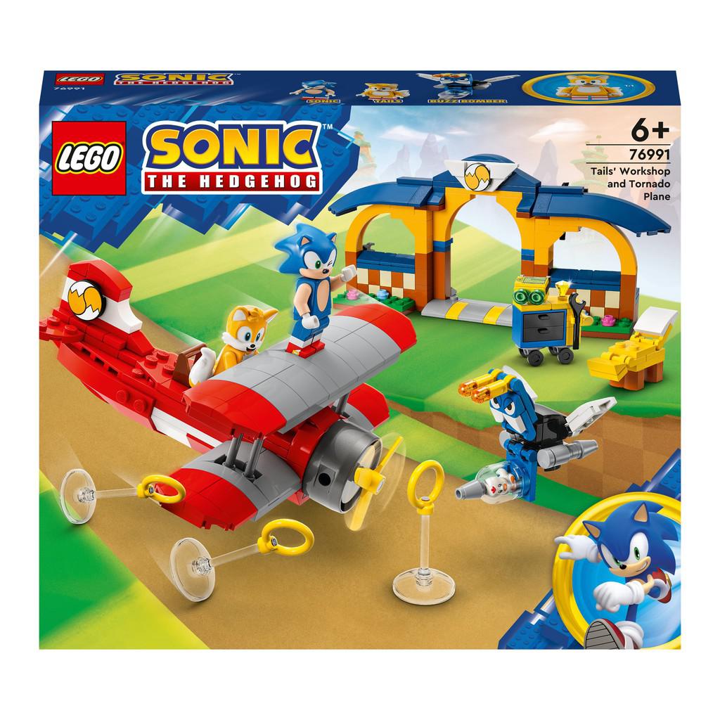this image showss the box for the LEGO Sonic the Hedgehog Tails Workshop and tornado plaine. sonic is standin gon a LEGO plane that tails is piloting there is a lego workshop in the back with yellow arches 