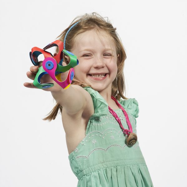 A girl holding colorful Clixo flower in a quad shape and smiling at the camera.