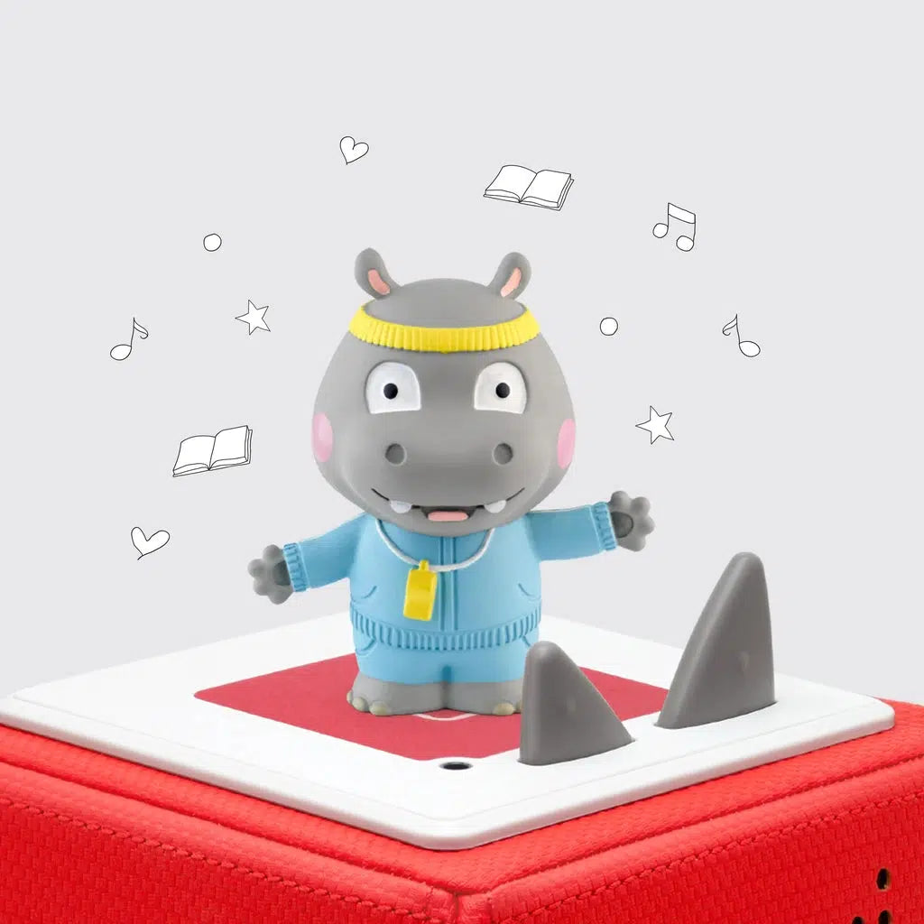 Tonie figure is a hippo standing on two legs and wearing a sweat suit and headband with a whistle around his neck