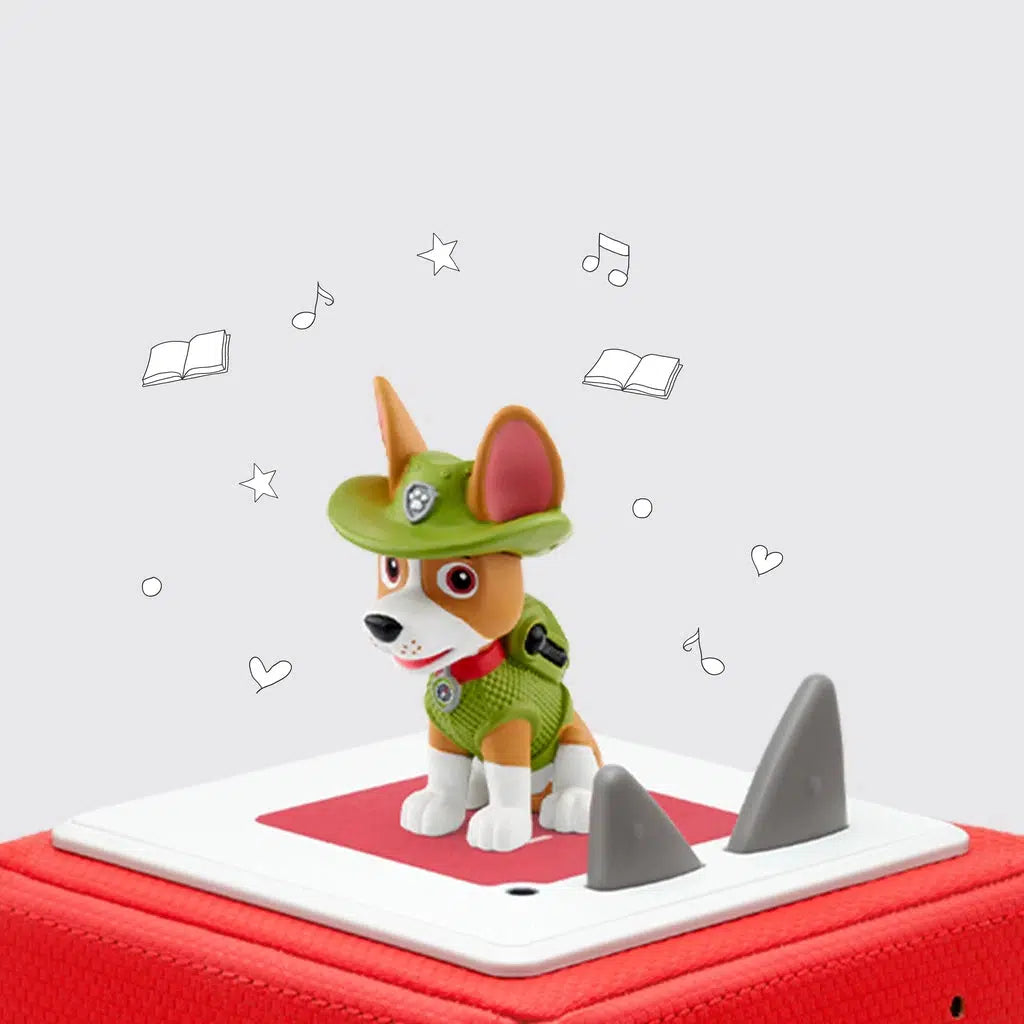 The tonie figure is shown on a toniebox. The figure is a brown and white dog with really large ears poking through holes on his green wide brimmed hat. He's also wearing a green vest and backpack