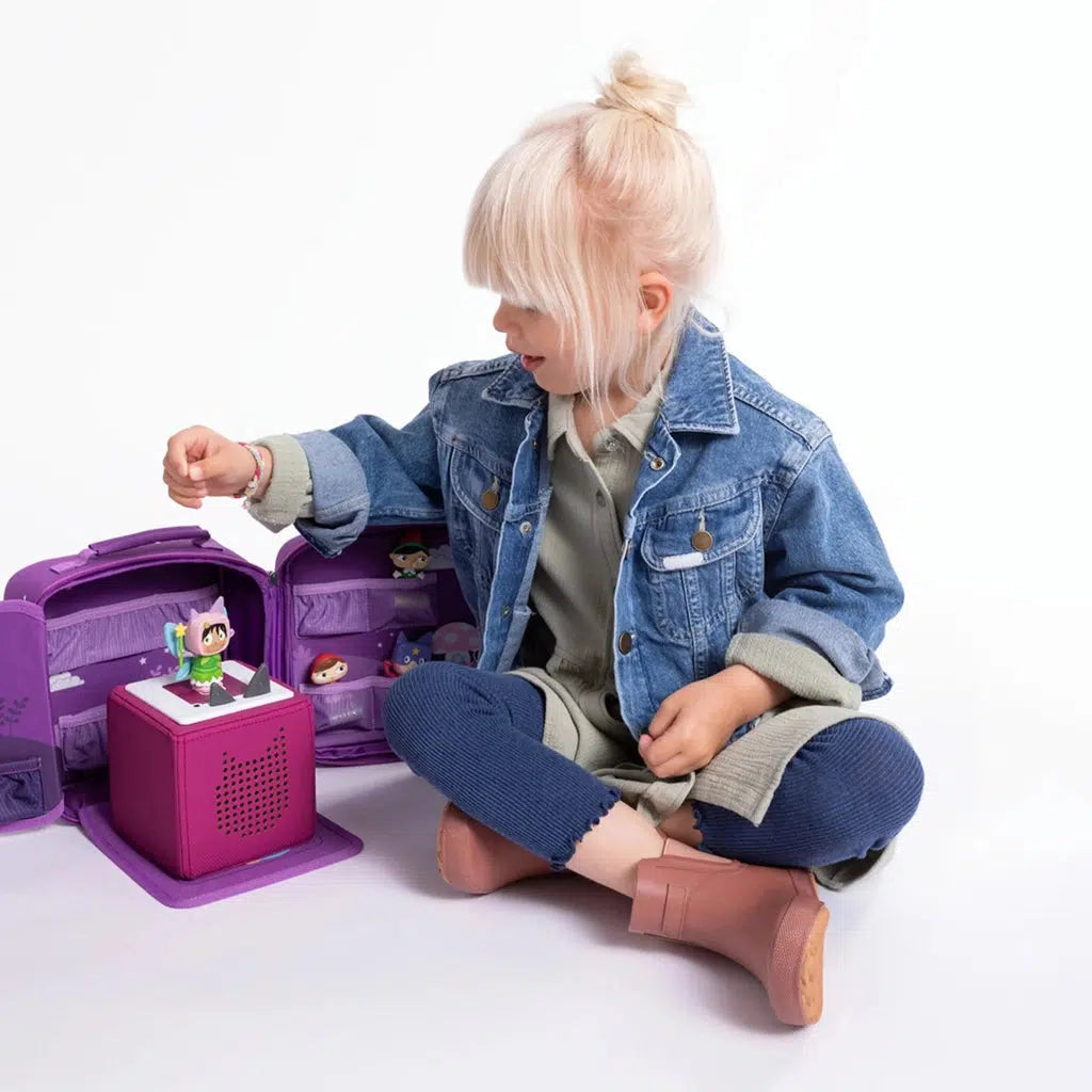 child playing with the case with the toniebox on the fold down placemat with a tonie figure placed on top