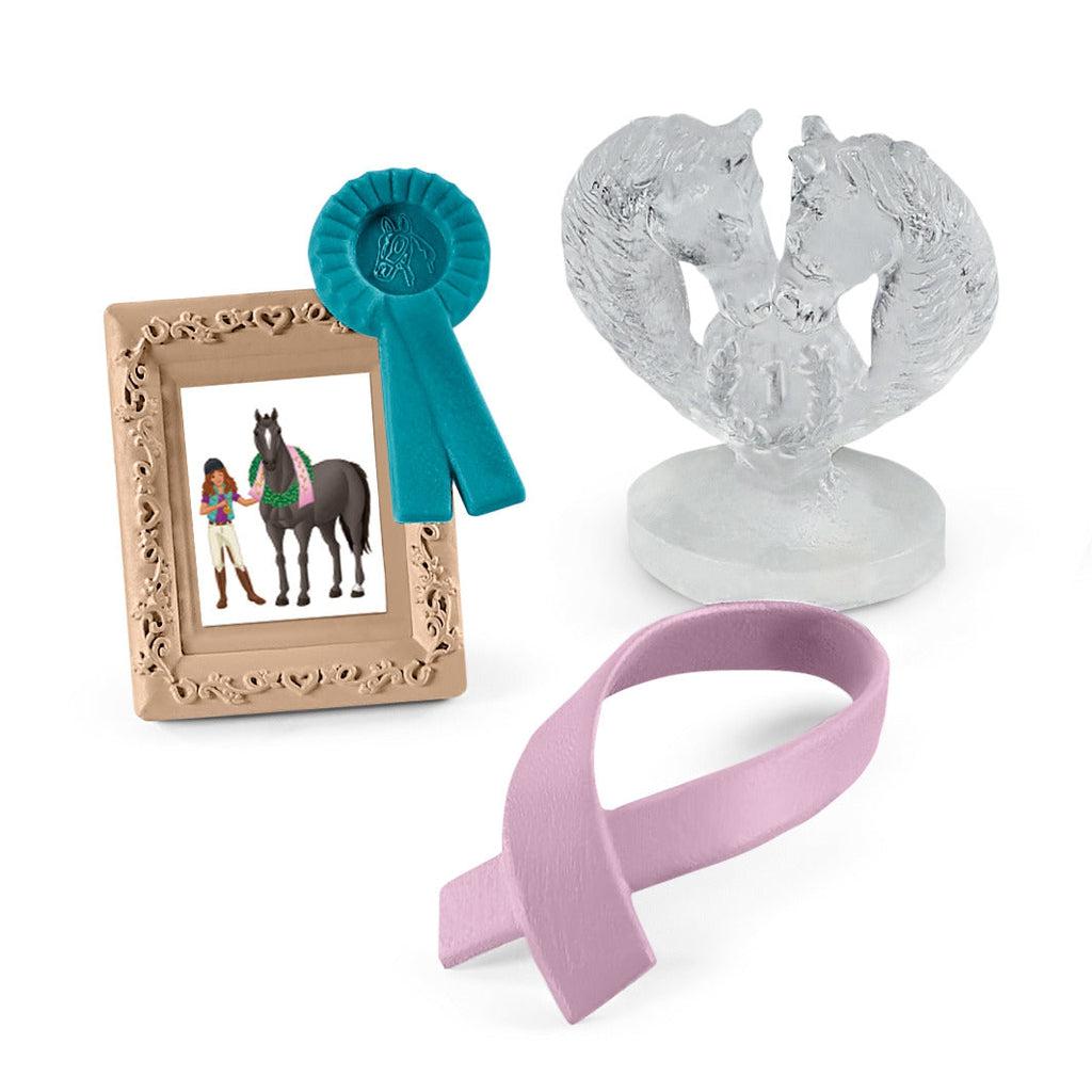 Image of the Tournament Accessories figurines. The set includes a picture frame, a blue ribbon, a horse ice sculpture, and a horse winners ribbon.