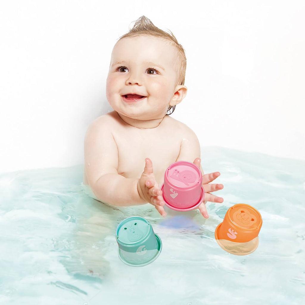 Scene of a baby playing with the cups in the bath.