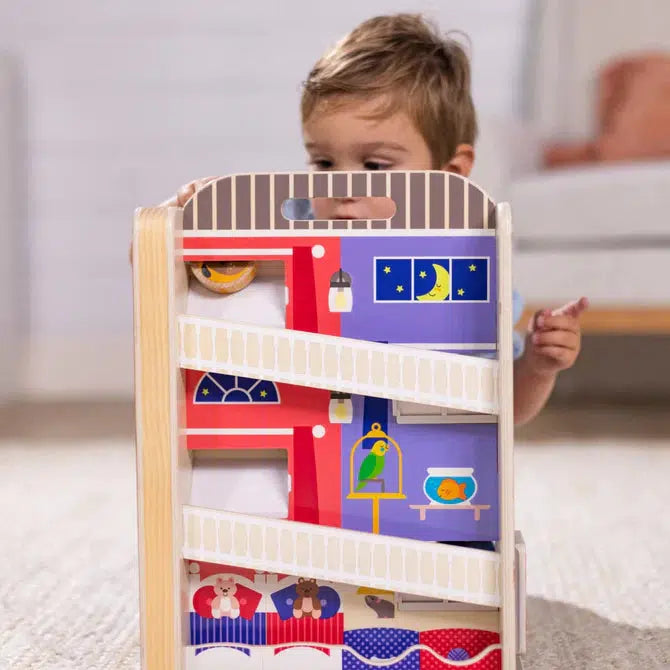 Scene of a little boy playing with the tumble toy. It shows that the back side of the toy has pictures showing that it is inside the apartment building instead of the outside. It also has a storage space for four of the people disks.