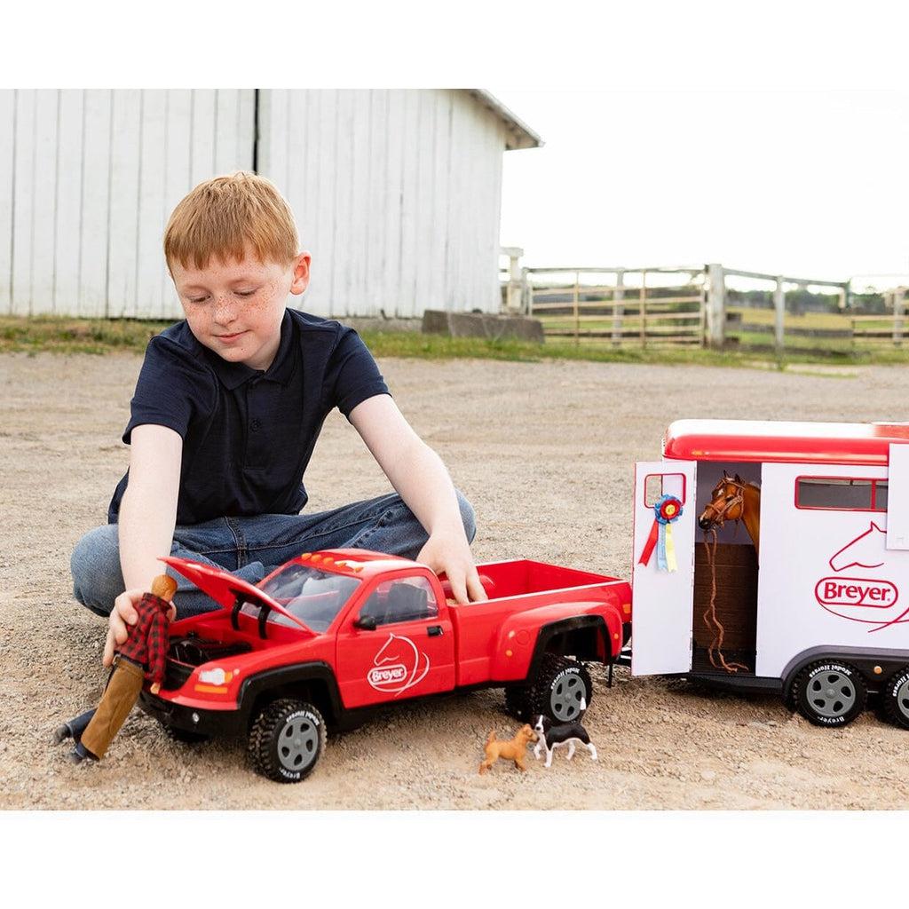 Scene of a little boy playing with the horse trailer.