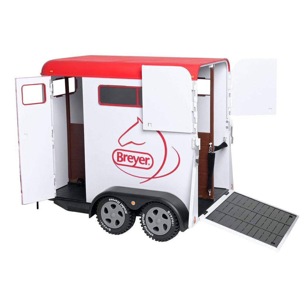 Image of the Traditional Series Two Horse Trailer. It is a white and red trailer with the breyer logo on the side. It comes with a horse ramp and a way to hook it up to a toy truck.
