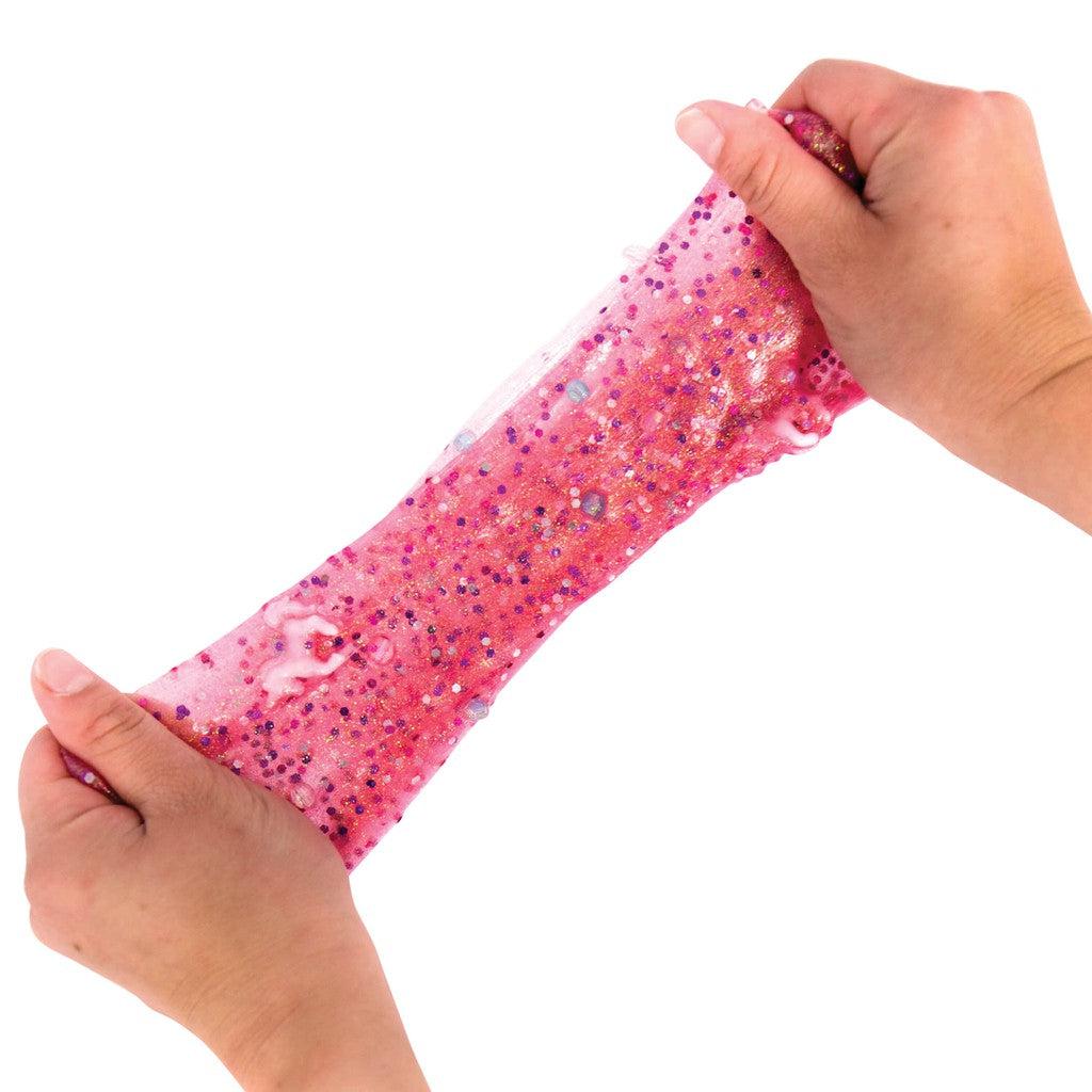 this image shows a child pulling and stretching the slime with the unicorns and glitter mixed in, stretching and pulling it