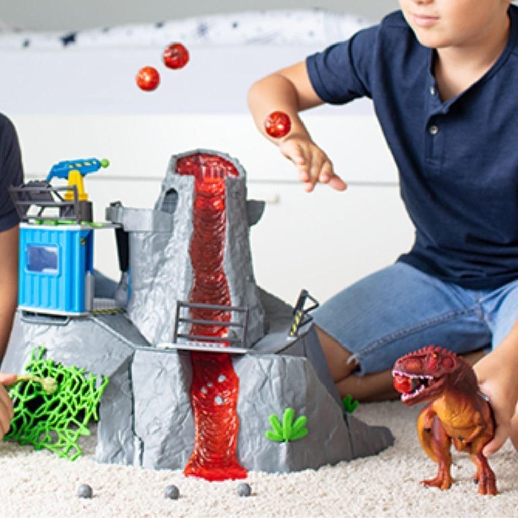Scene of a little boy playing with the Volcano Expedition Base Camp. It shows his holding the T-rex and deflecting lava boulders.