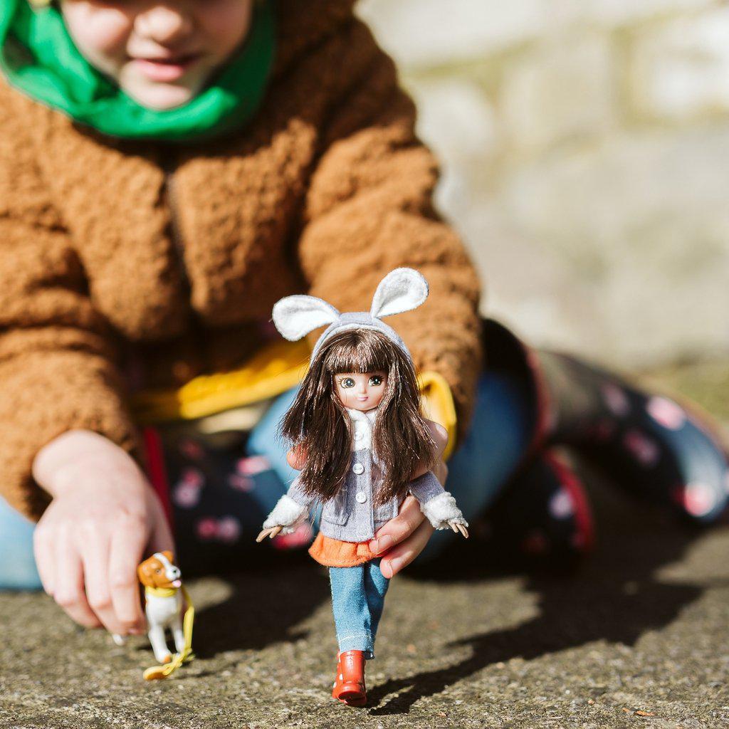 a girl having the doll and dog walk around on the ground