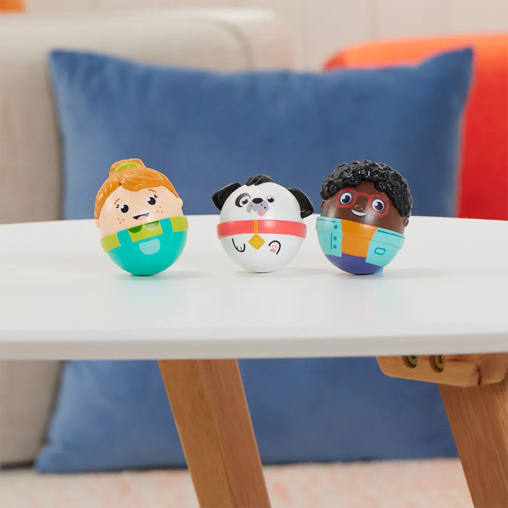 this image shows the three weebles wobbling on a table! they are smiling. 