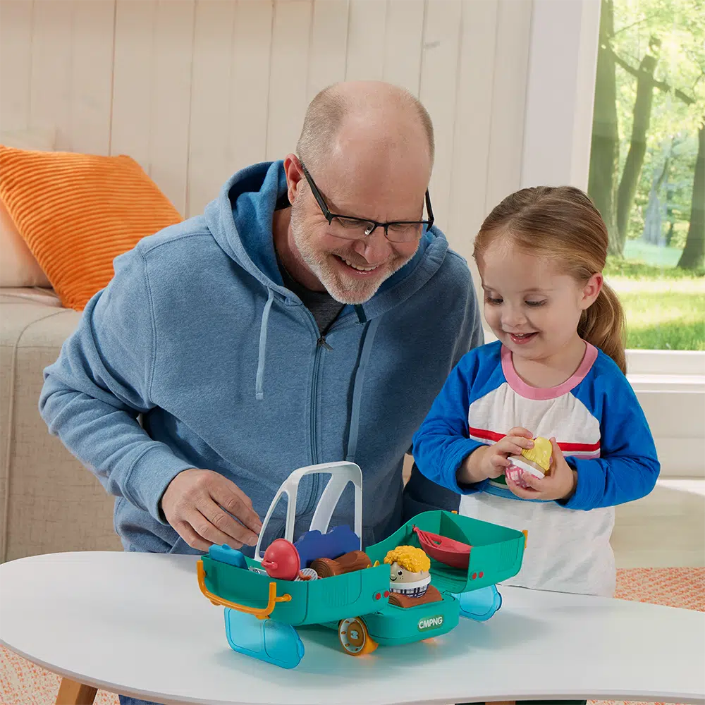 this image shows a dad and daughter playing with the weebles happy camper, the camper has opened up for playtime fun side the van