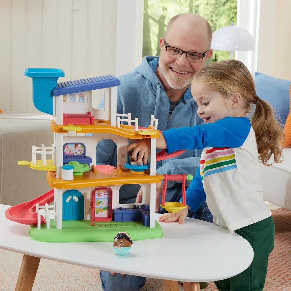 this image shows a dad and daughter playing with the weebles house set! look the boy weeble, Louis is going down a slide