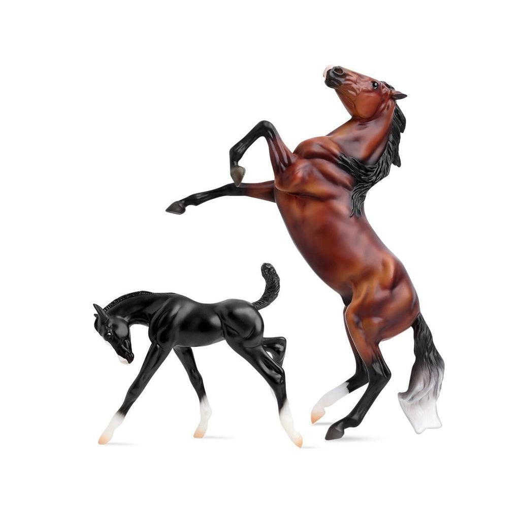 Image of the two horse figurines outside of the packaging. The larger horse is red-brown with black mane, tail, and legs. The foal is completely black with white hooves.