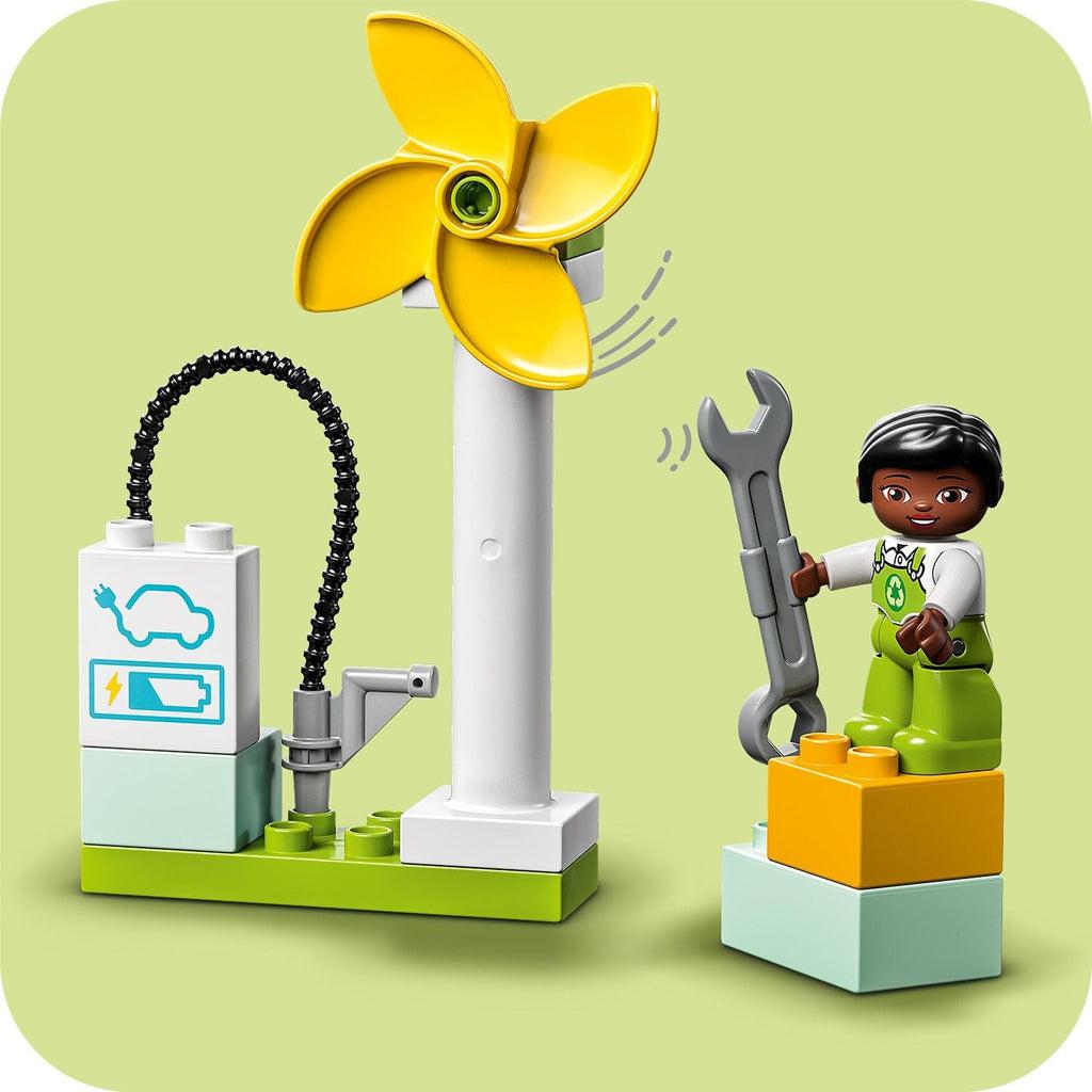 character figure standing on blocks next to the wind turbine and charging station, motion lines indicate the turbine spins