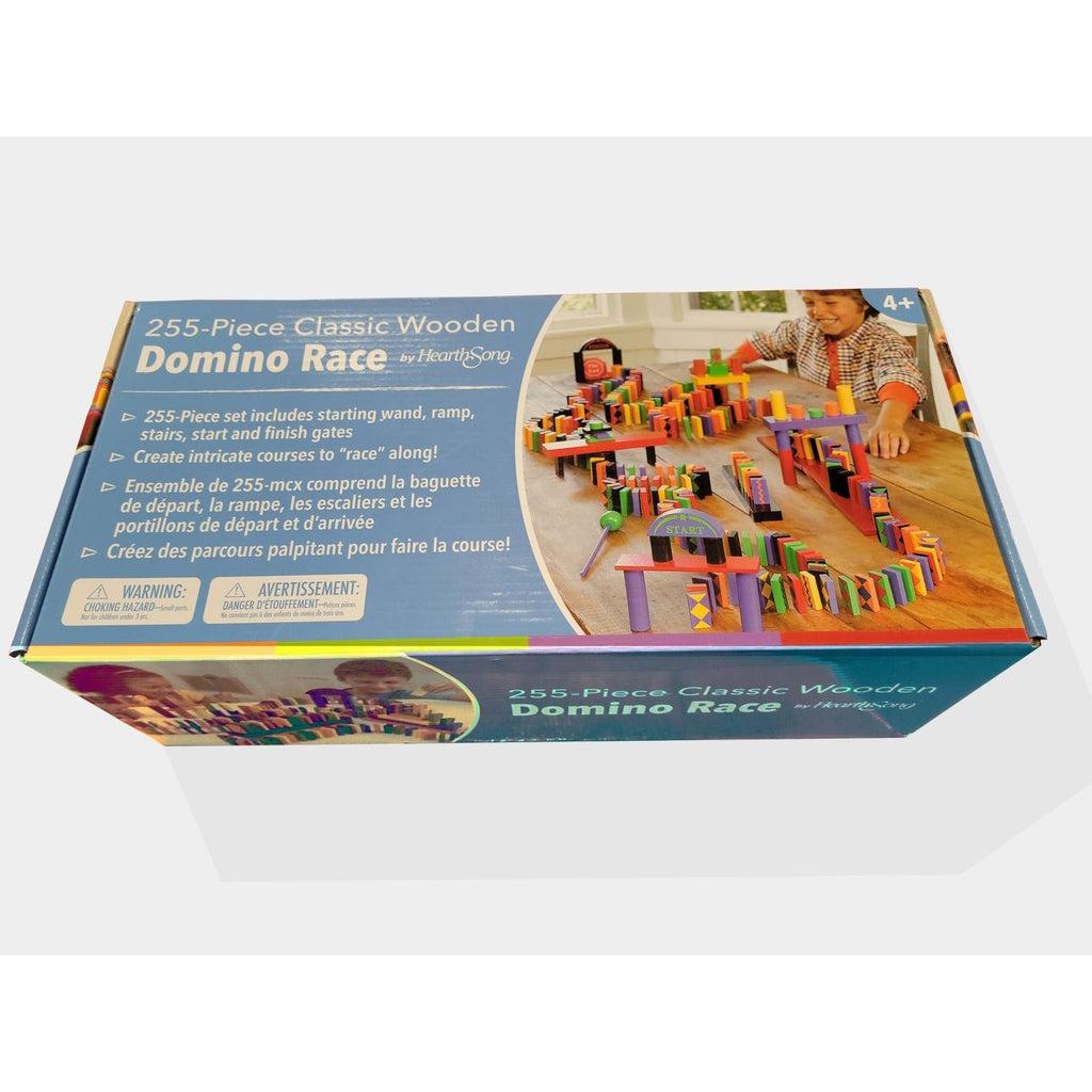 The wide box with a blue background reads: "255-Piece classic wooden domino race by hearthsong" 255 piece set includes starting wand, ramp, stairs, start and finish gates. create intricate courses! There is a choking hazard warning in the bottom left. There is an image of a boy sitting at a table smiling at a winding domino track he has set up.