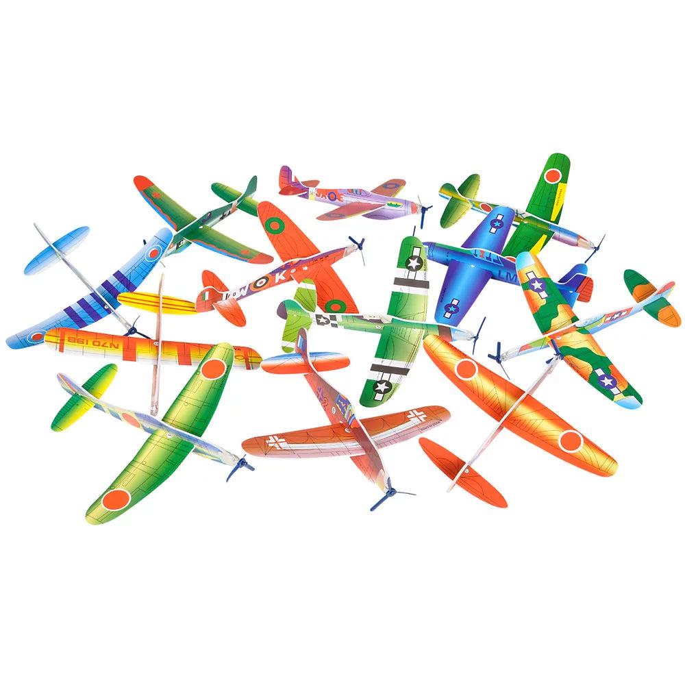 A pile of foam gliders displaying all the different styles. Including a green plane with yellow gradients on the wings and a red dot on the wingtips, another exactly like that but with yellow bars instead of gradients, a green one with black bars on the wings, a red and yellow one, a red and green one, a red one styled like a real plane, a blue one with dark blue stripes, and a blue one styled like a real plane