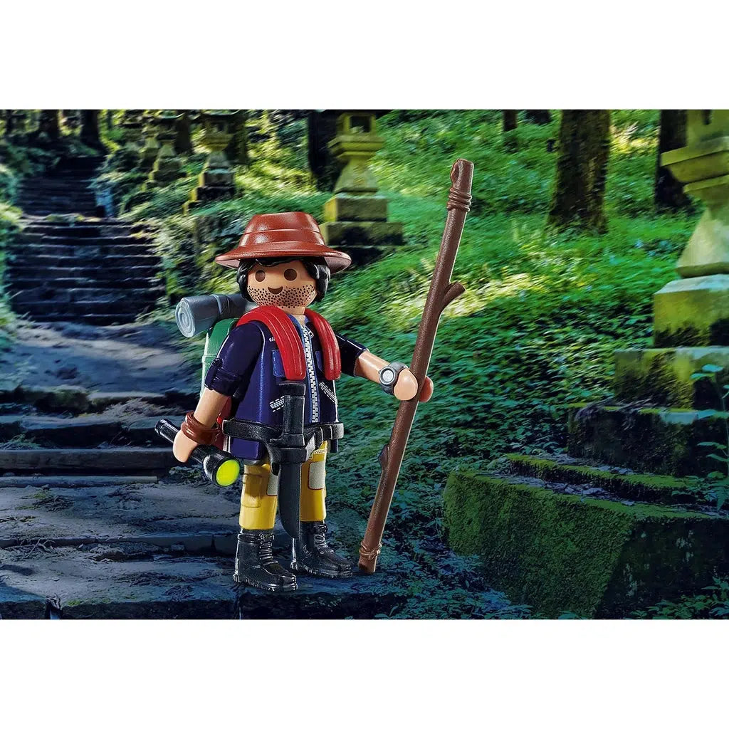 Scene of the Adventurer holding all of his gear. He has a hat, a walking stick, a backpack, a flashlight, and he is wearing a jacket and boots.