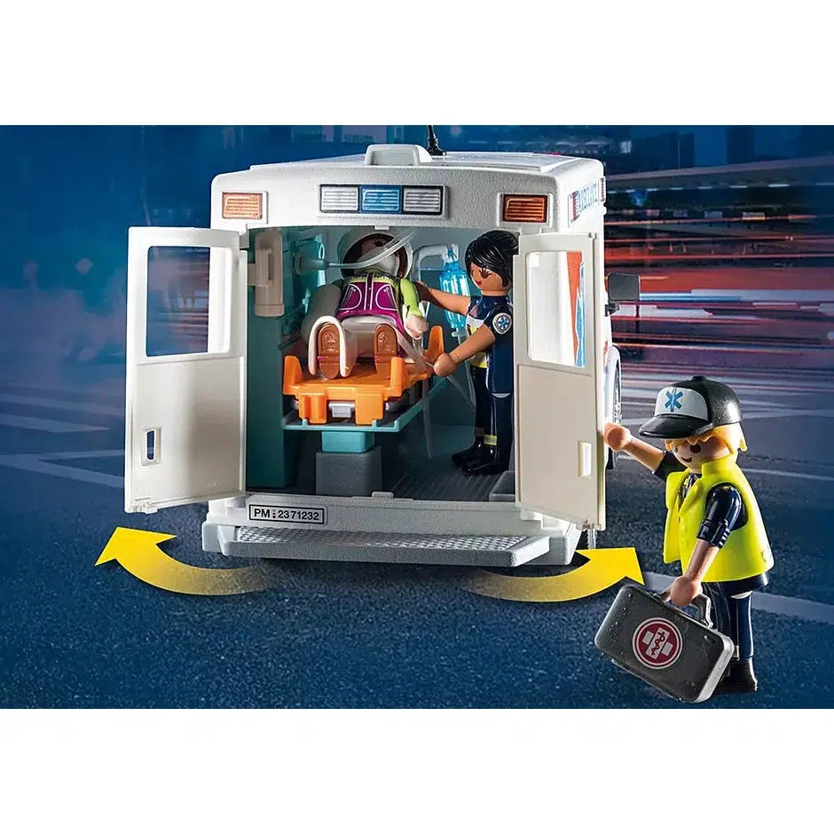 Image shows the backdoors opening with the stretcher and 2 figures placed inside the ambulance while the third figure stands outside it with a med kit in hand
