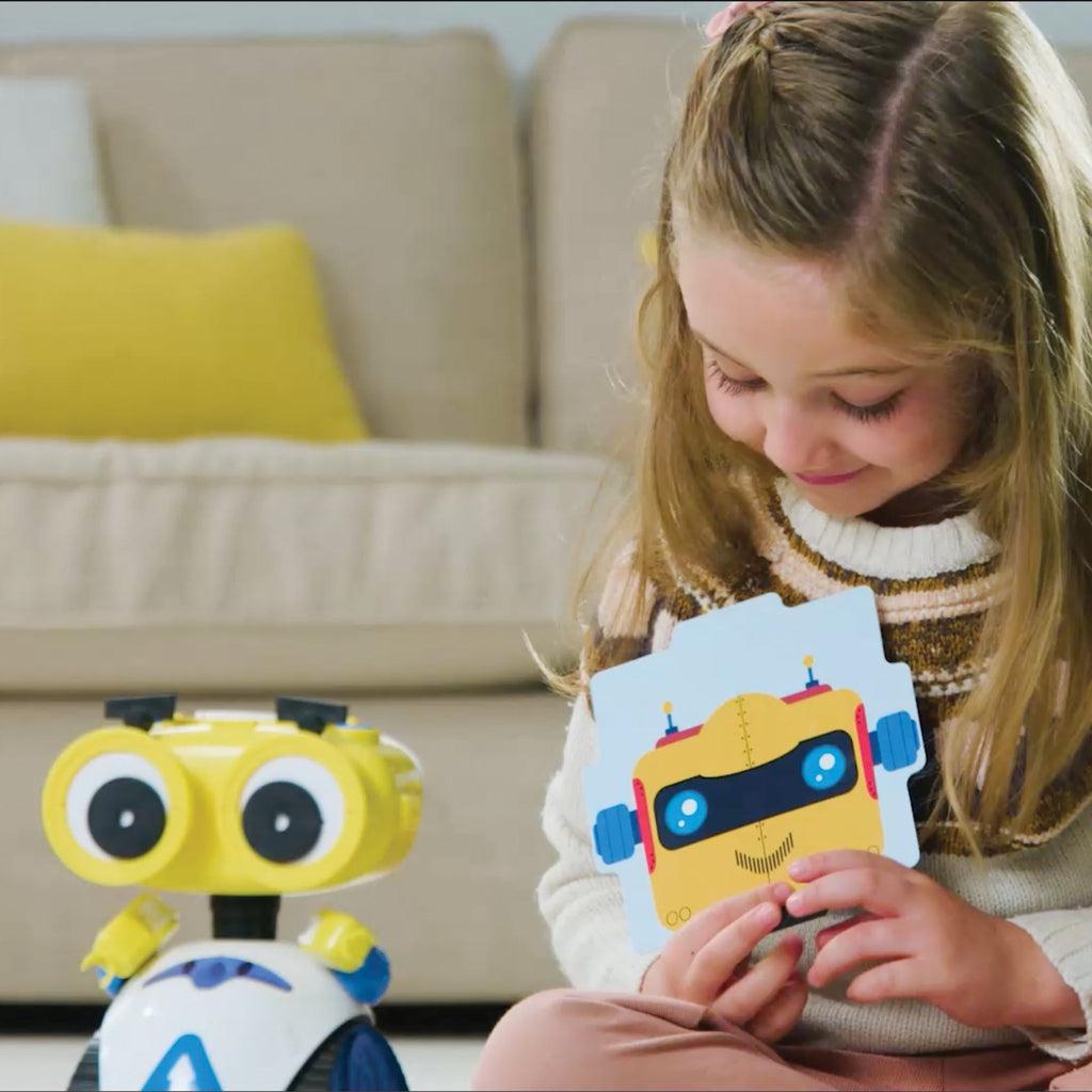 Image of a young girl holding a carboard robot card and playing with robot. 