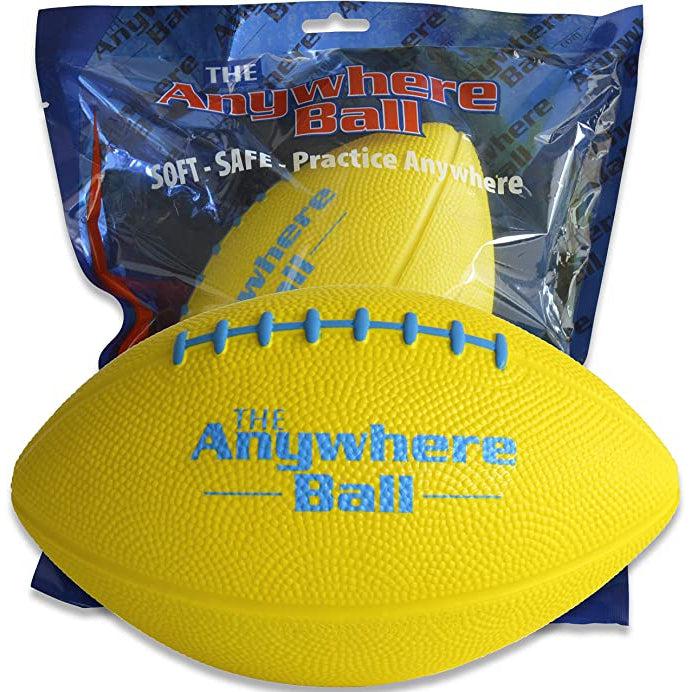 A foam football with blue highlights on the fake stitching and on the text: "The anywhere ball" sits in front of another anywhere ball football in vacuum sealed packaging. The packaging reads: "The anywhere ball. Soft - Safe - Practice anywhere"
