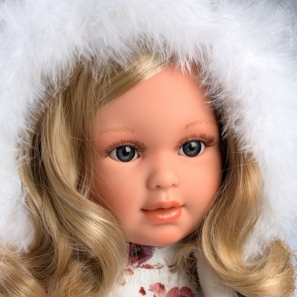 Close up of doll's face | Close-up reveals the doll to have life-like skin and painted blonde eyebrows. The doll has long realistic blonde eyelashes.