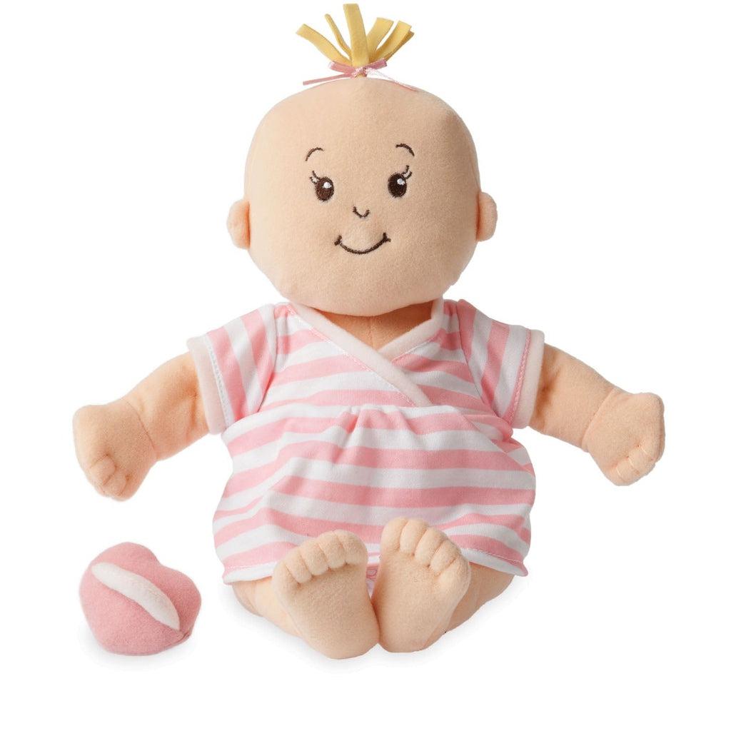 The peach Baby doll is shown out of the box sitting down next to the pacifier. Its hair is a handful of thick fabric strands in a tuft at the top of the head.