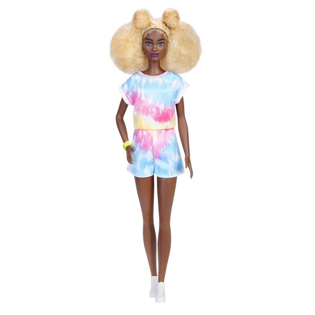 Example doll | This doll has curly blonde hair styled into an afro with buns, hazel eyes, and a dark tone. She is wearing a blue/red/yellow tie-dye romper with white sneakers and a green bracelet.