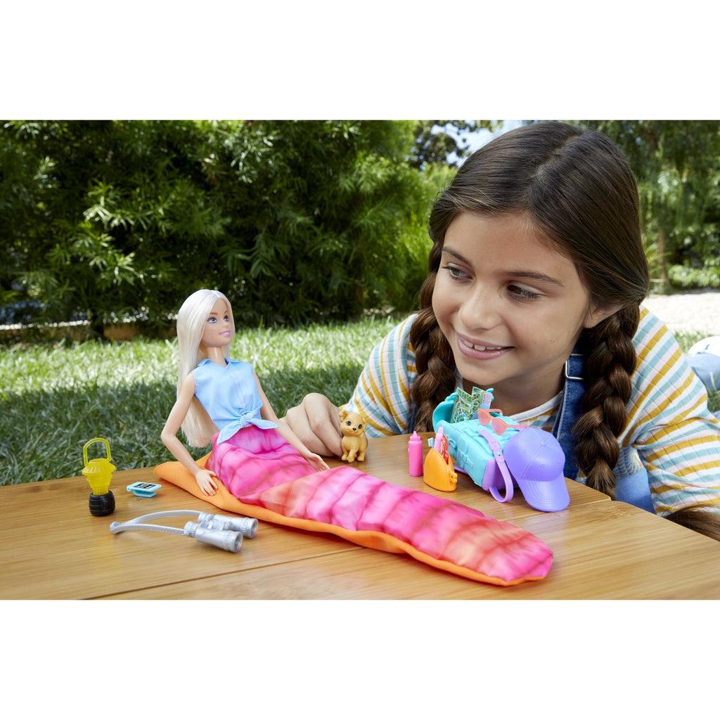 Scene of a little girl smiling and playing with the camping Barbie while on her own camping trip.