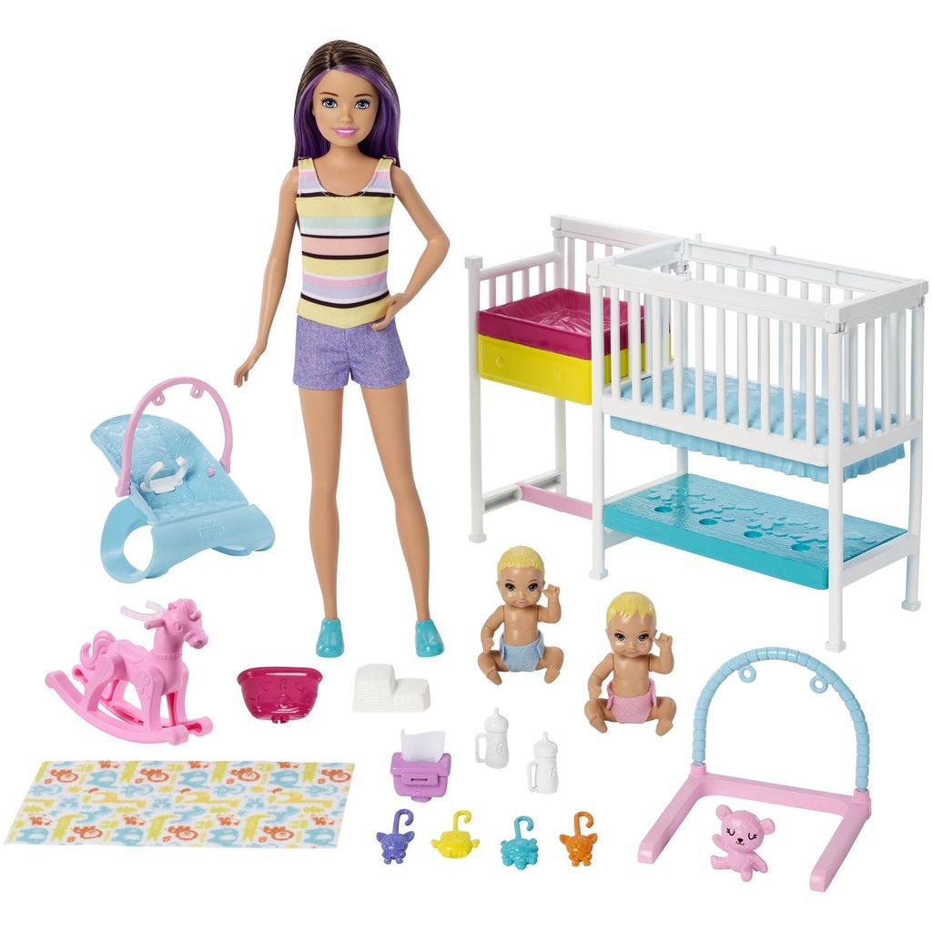 Image of all the included pieces in the set. It includes a Skipper doll, two baby dolls, a crib with attached changing station, baby toys, and tools like bottles and whips.