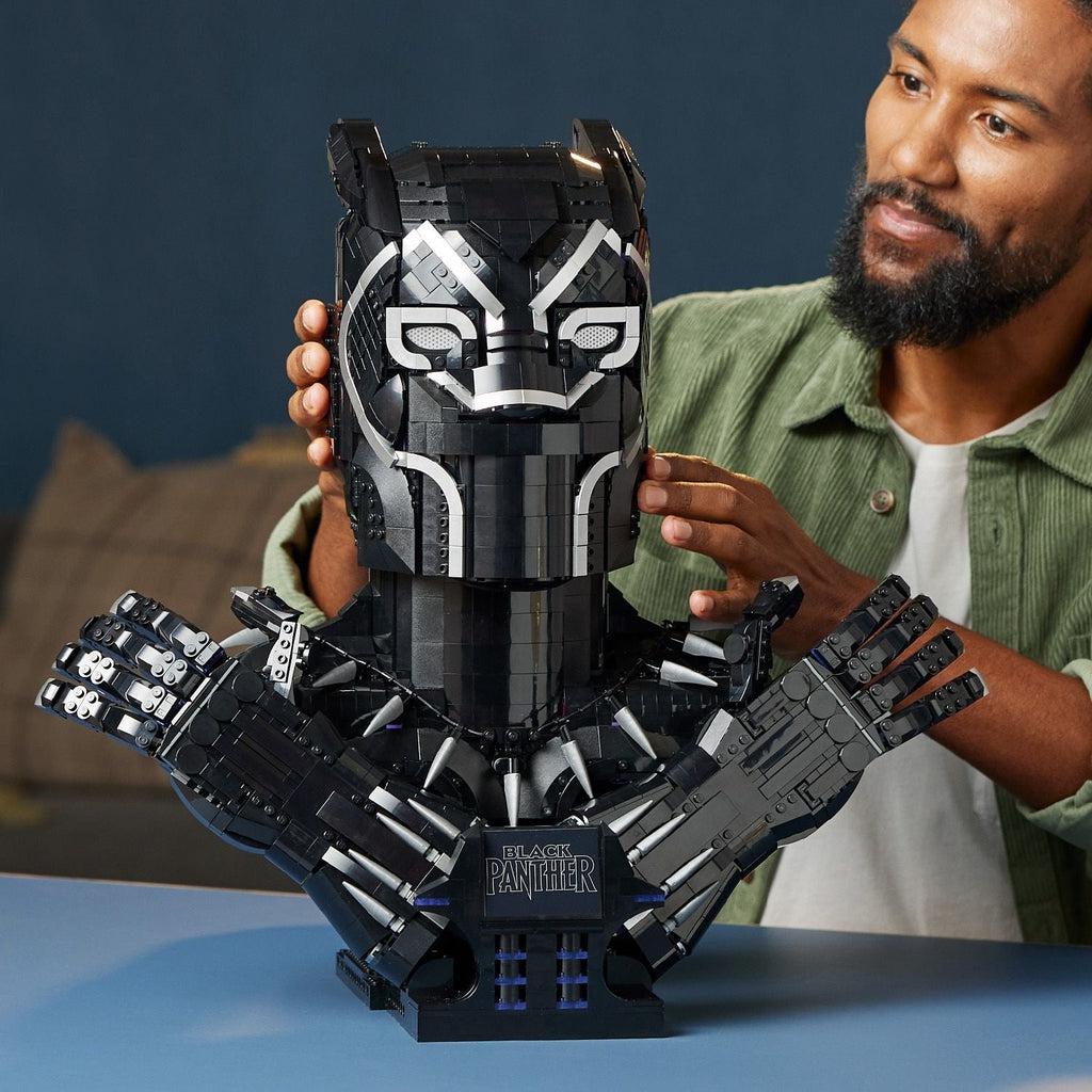 a man looks proudly at the finished black panther lego set display