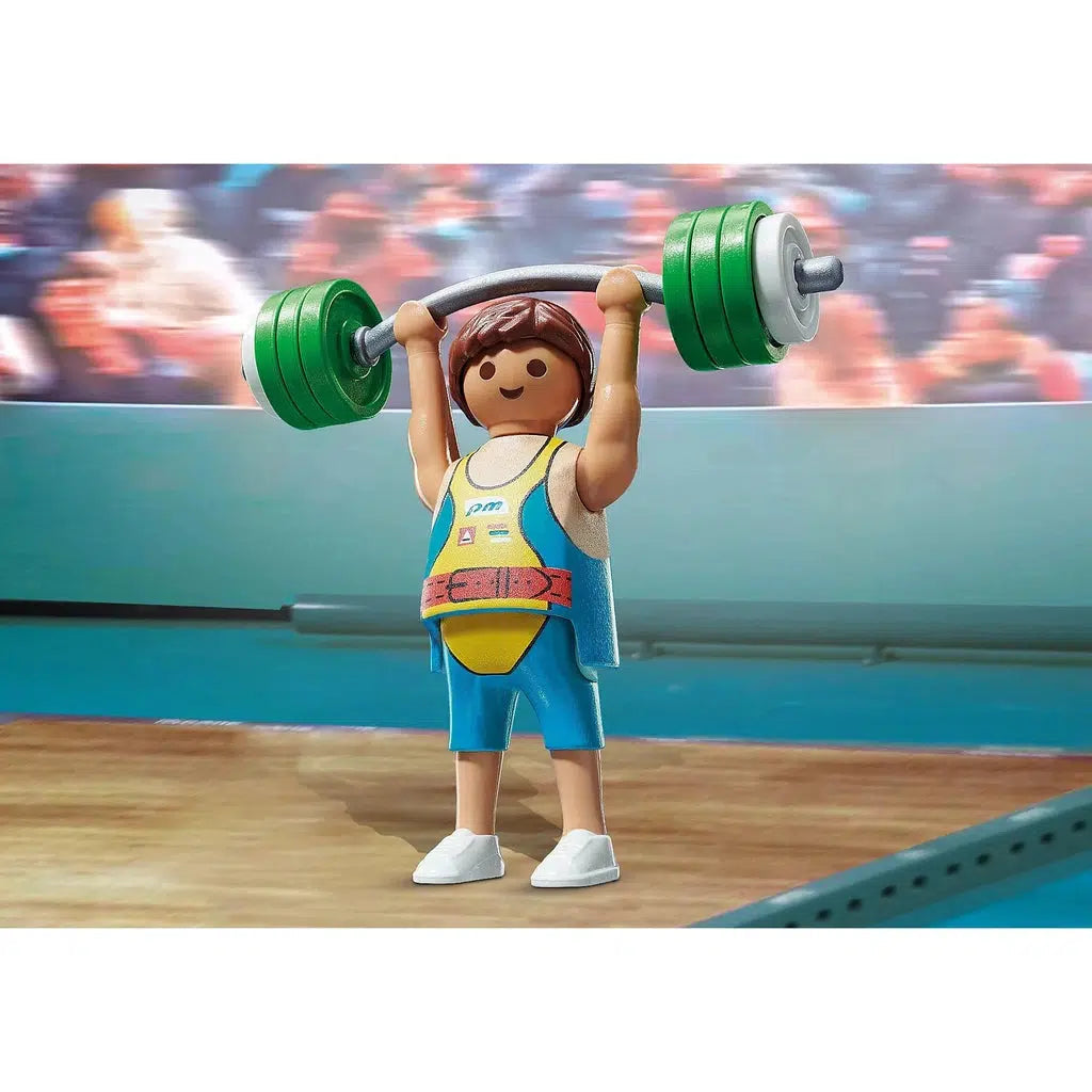 Scene of the Bodybuilder holding the Olympic bar above his head. He is wearing a blue and yellow leotard and the weights are silver and green.