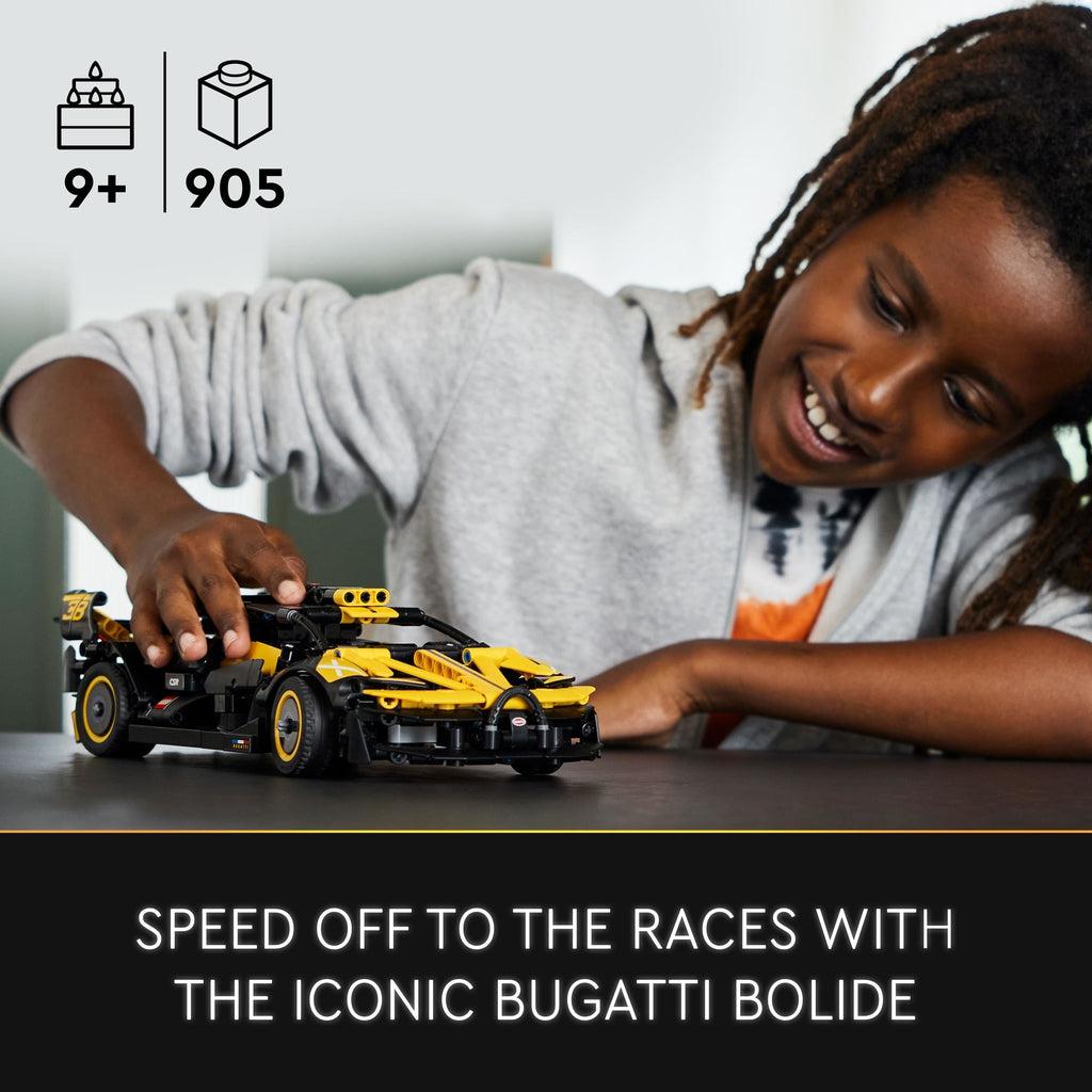 a child is playing with the lego car on a table | piece count of 905 and age of 9+ in top left corner | image reads: Speed off to the races with the iconic bugatti bolide