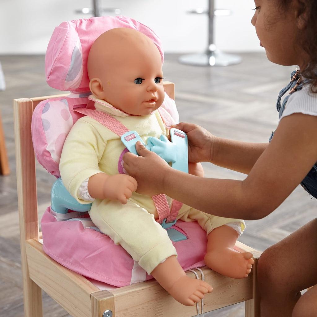 A girl is shown connecting the buckle at the front of the seat to secure the doll she has placed in the seat
