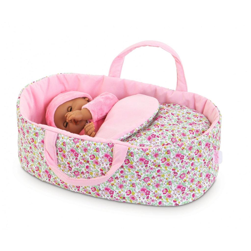 The carry bed is shown with a baby doll inside it. It's a white background with a thick pattern of pink flowers and green stems and vines. The inside of the bed is a solid light pink.