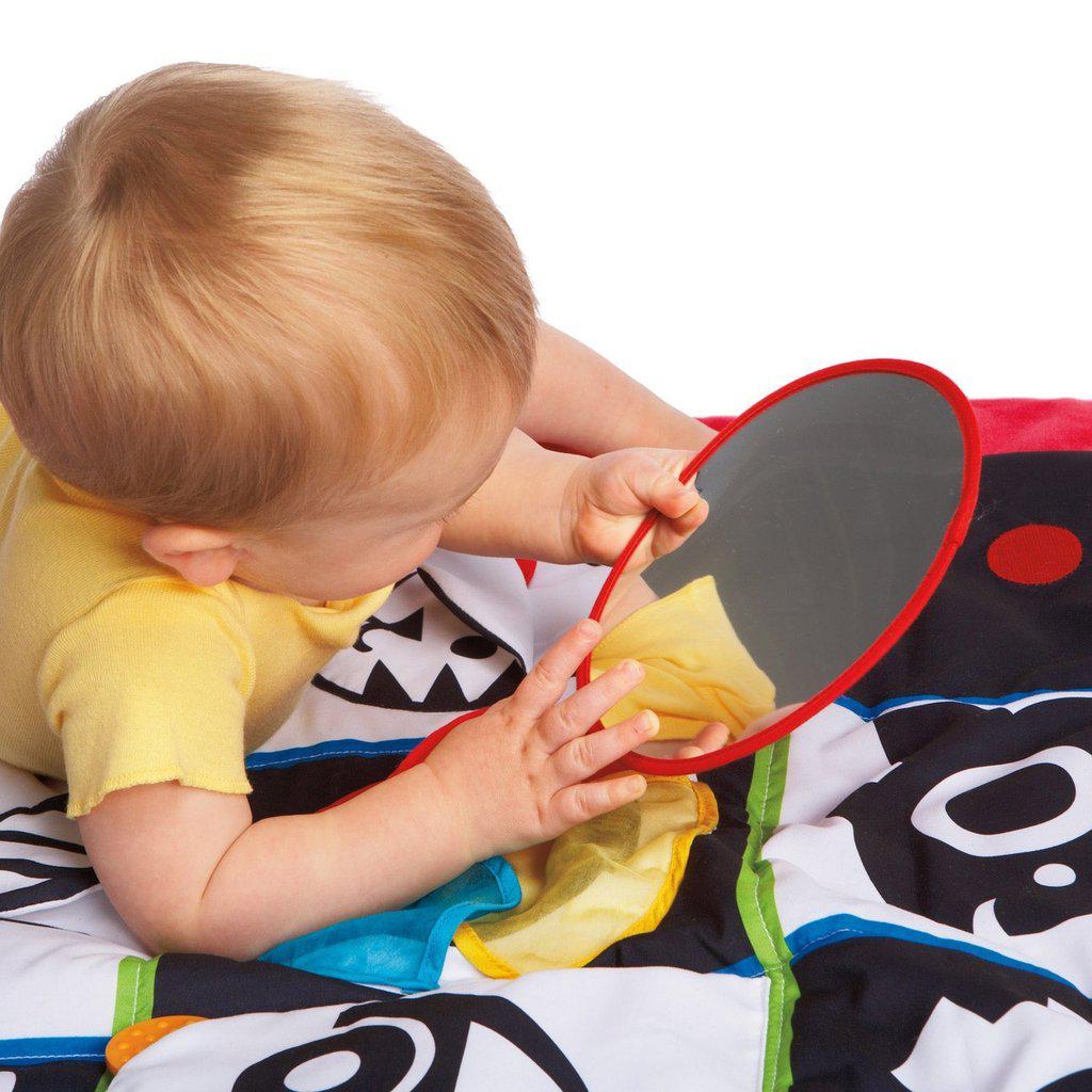 Scene of a baby playing on the mat. It shows that the mirror can be detached and reattached with velcro.
