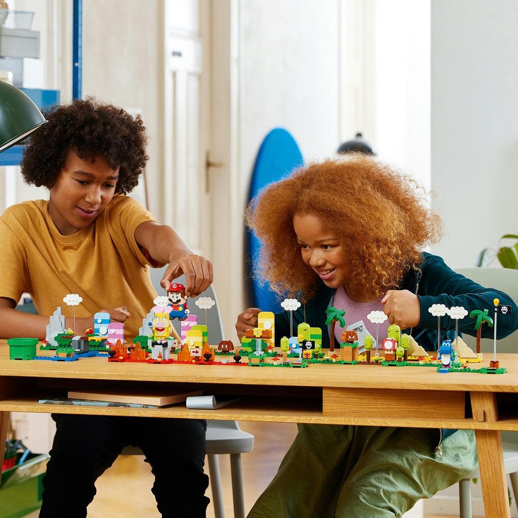 two children play with the lego set on a table, they also have the mario figure from the base lego super mario set
