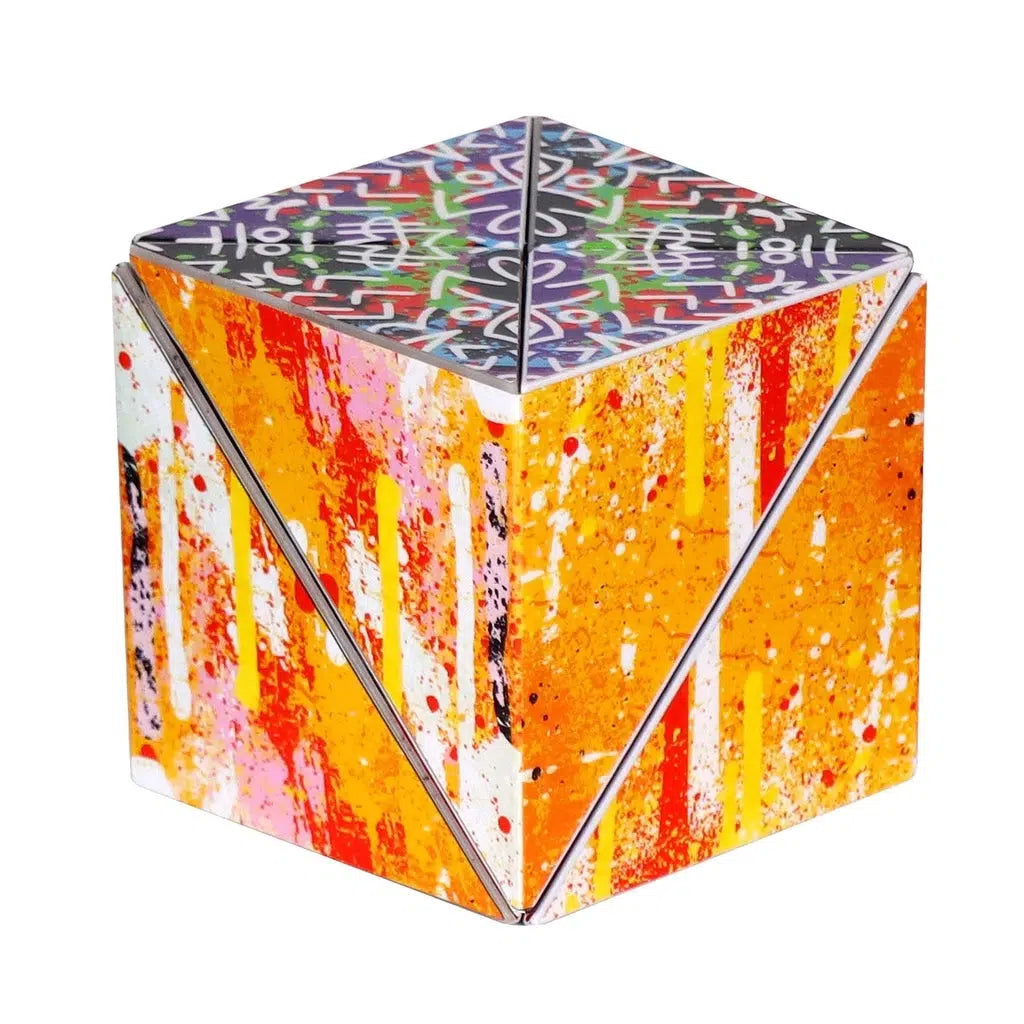 A cube made of segmented triangular pieces so that it can unfold and twist into new shapes. It's covered in splashes of orange and pink on the sides and a psychodelic pattern on the top