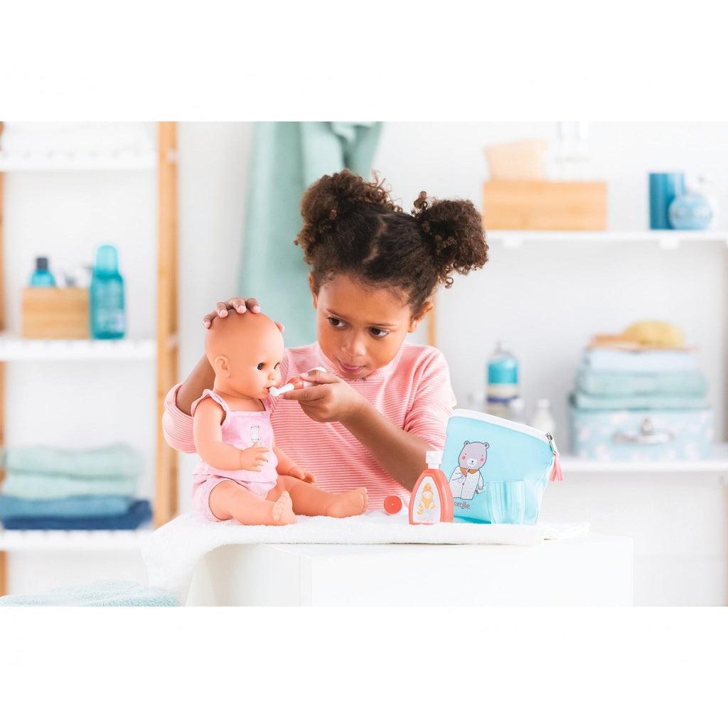 A small girl is shown brushing her dolls teeth with the included toothbrush