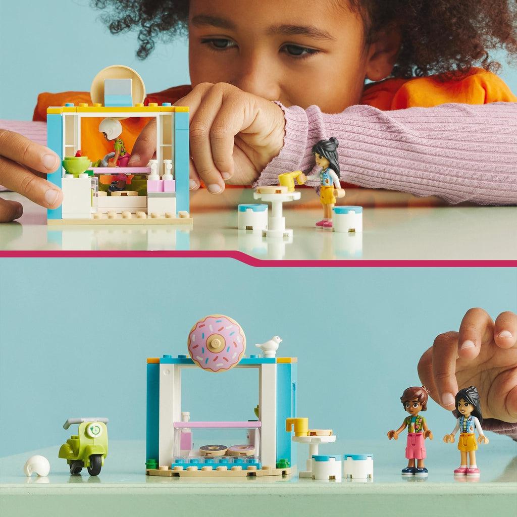 Top image shows a young girl playing with the lego set | bottom image shows the playset spread out with the scooter on the left of the shop and the two characters and the table to the right.