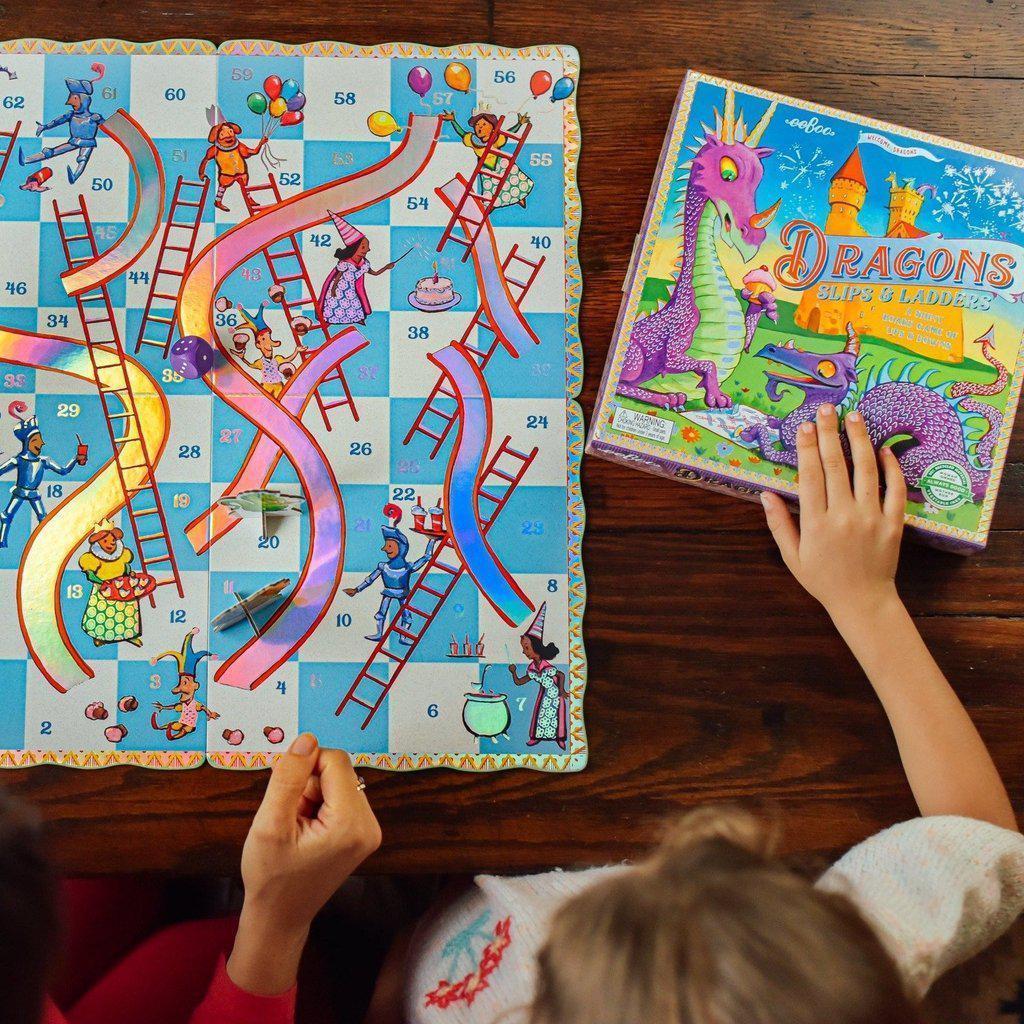 a child is holding the box and board game of slips and ladders with a dragon theme