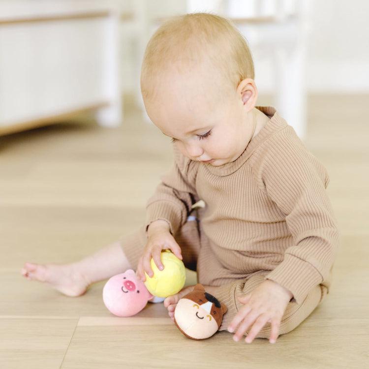 Baby sitting on floor playing with pig, chicken, and horse toys