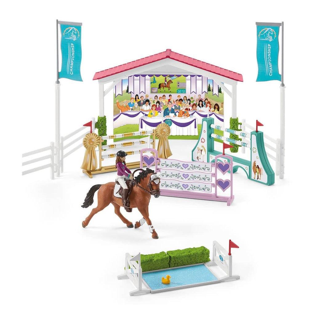 Image of the full set outside of the packaging. It includes am overhang with a judge and a crowd, a horse with a rider, three different hurdles, and  a hedge with a duck pond that can also be used as a hurdle.