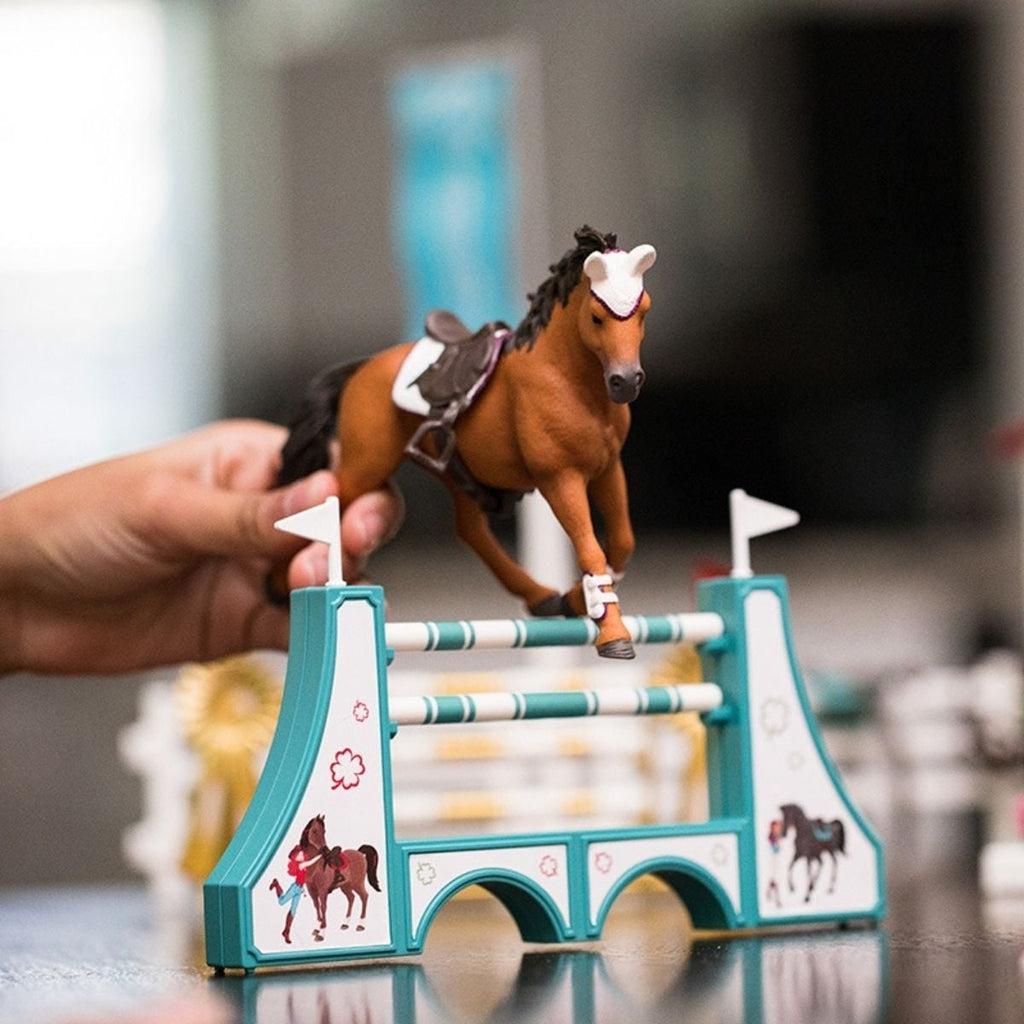 Scene of a little girl playing with the horse as it jumps over the hurdles.