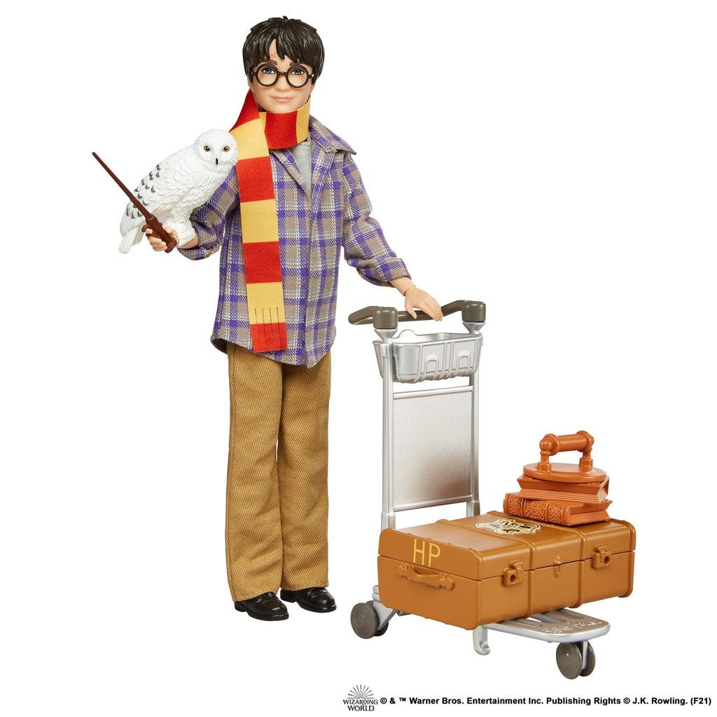 Doll with owl and wand on right arm, other accessories sit on the luggage cart.