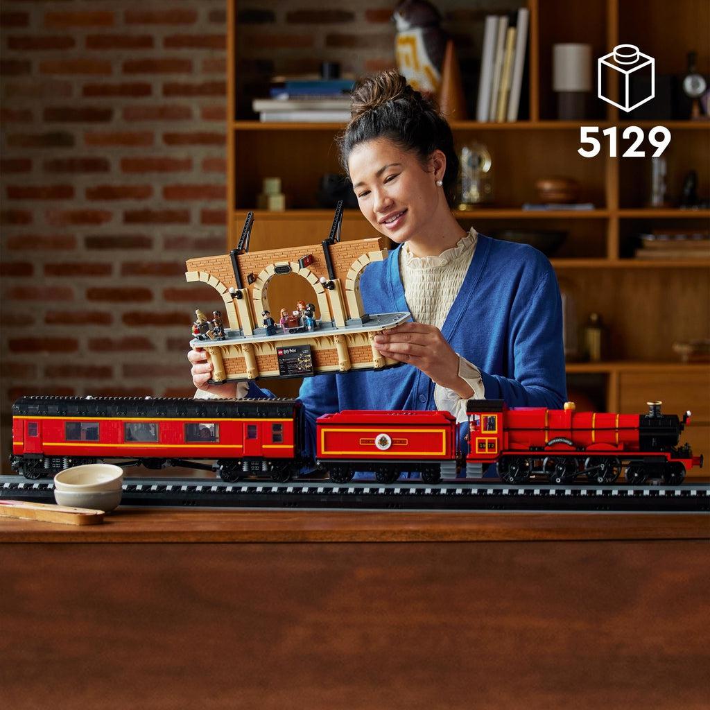 A woman is shown holding the boarding platform to examine it while the train is sat on a table in front of her. | piece count of 5129 is shown in the top right corner