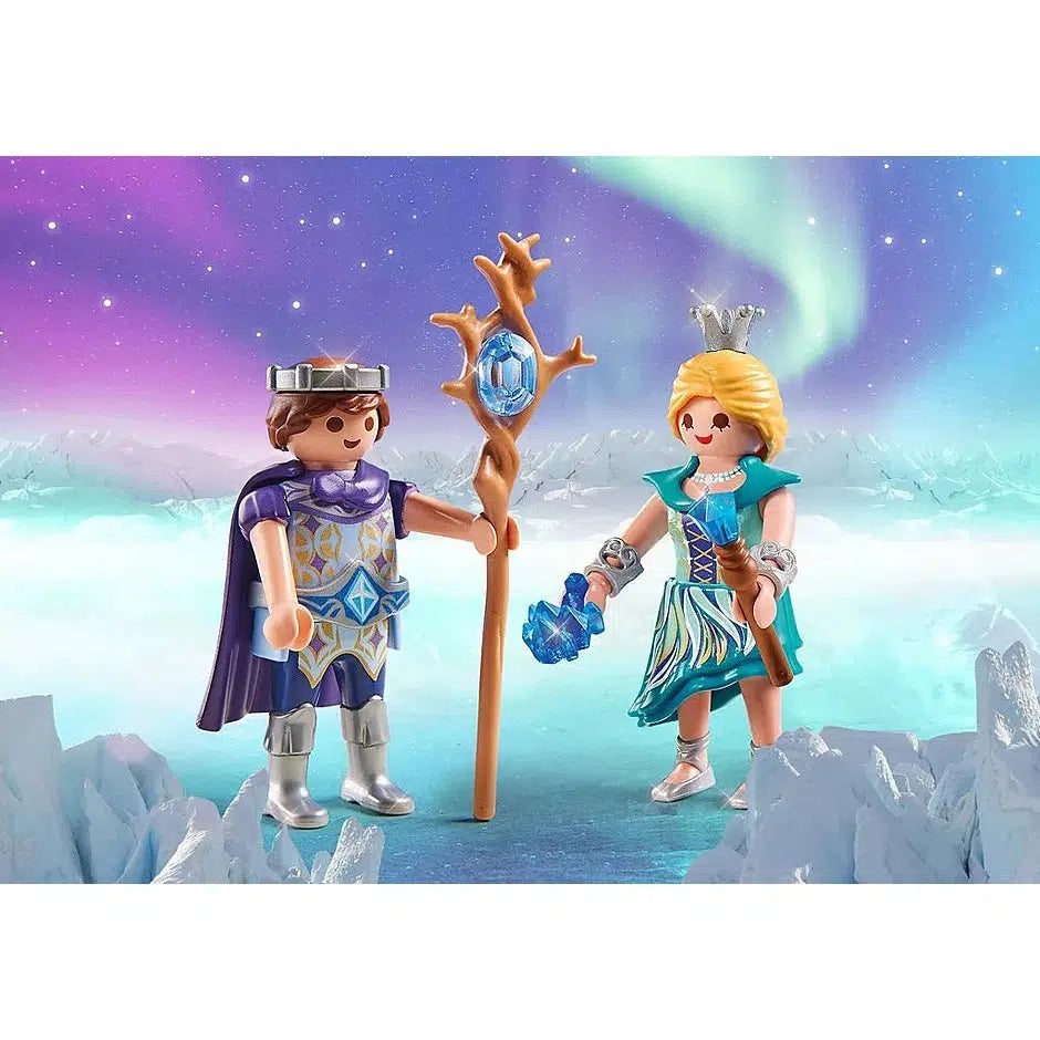 The ice prince on the left is wearing a thin circular silver crown and holding a twisted staff with a blue gem at the tip. The ice princess holds a wand with blue gem as well as another blue jewel in the other hand, she's also wearing a tall silver crown on top of her head