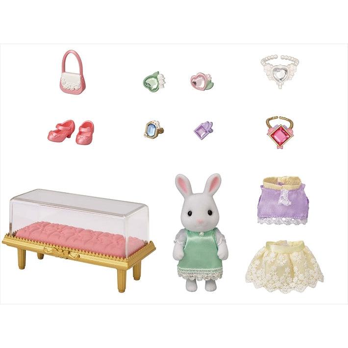 Image of all the included parts outside of the packaging. It includes a display case, a rabbit doll character, two dresses, shoes, a purse, bracelets, and necklaces.