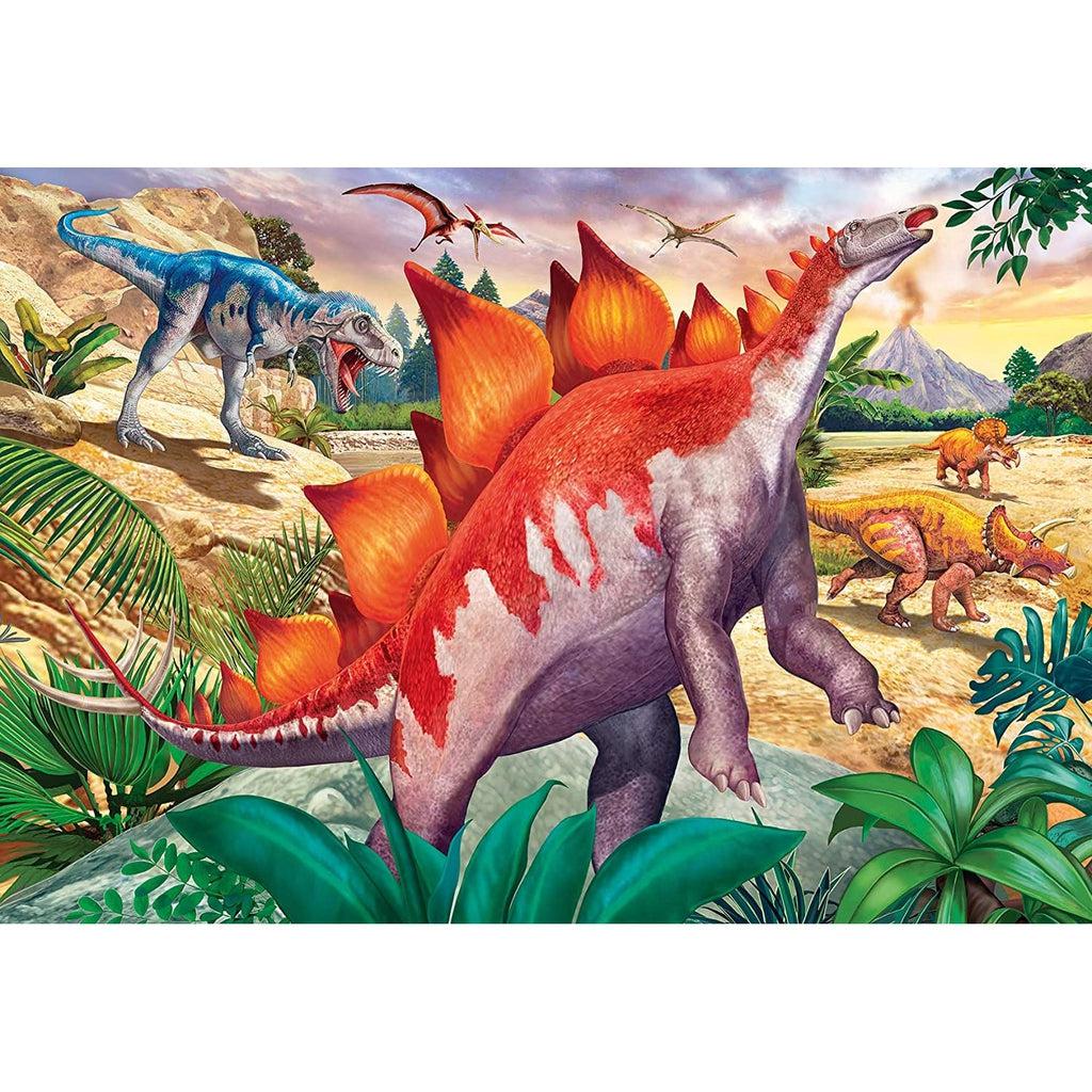 Image on puzzle 1 | Gray & orange stegosaurus stands on hind legs reaching for leaves. Background is a prehistoric landscape with a T-rex, triceratops, and pterodactyl. 